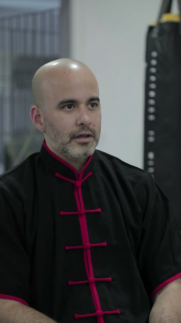 El Sifu, de traje negro con vivos rojos, explica qué es el linaje en la sala de la academia