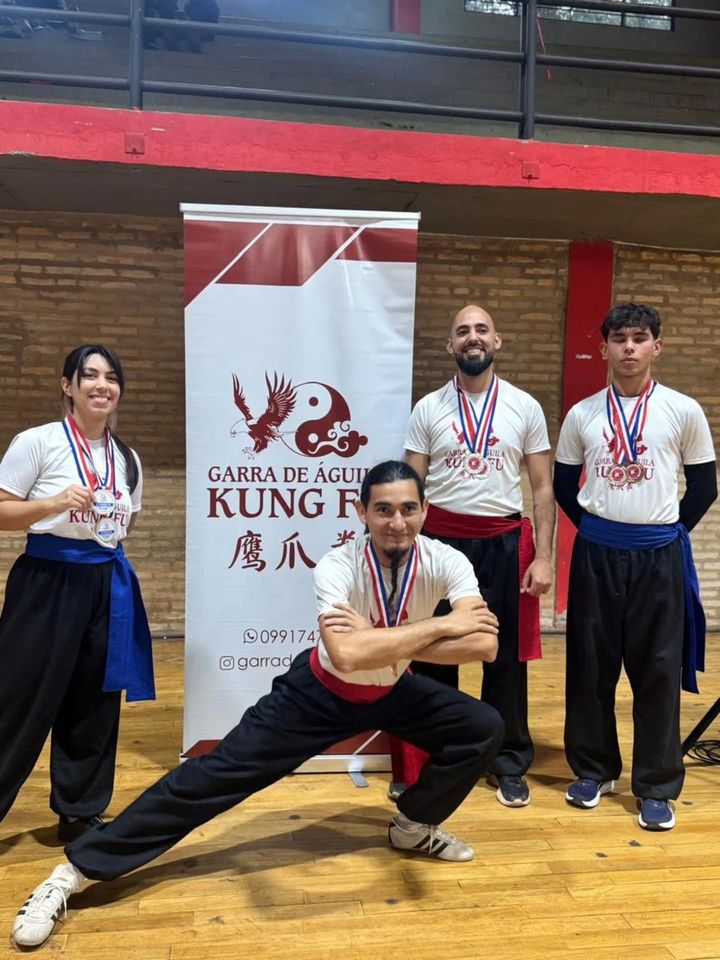 Alumnos y maestros con medallas frente al banner de la academia