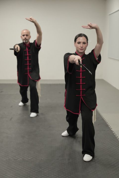 Dos practicantes ejecutan una forma con espada en la sala de entrenamiento