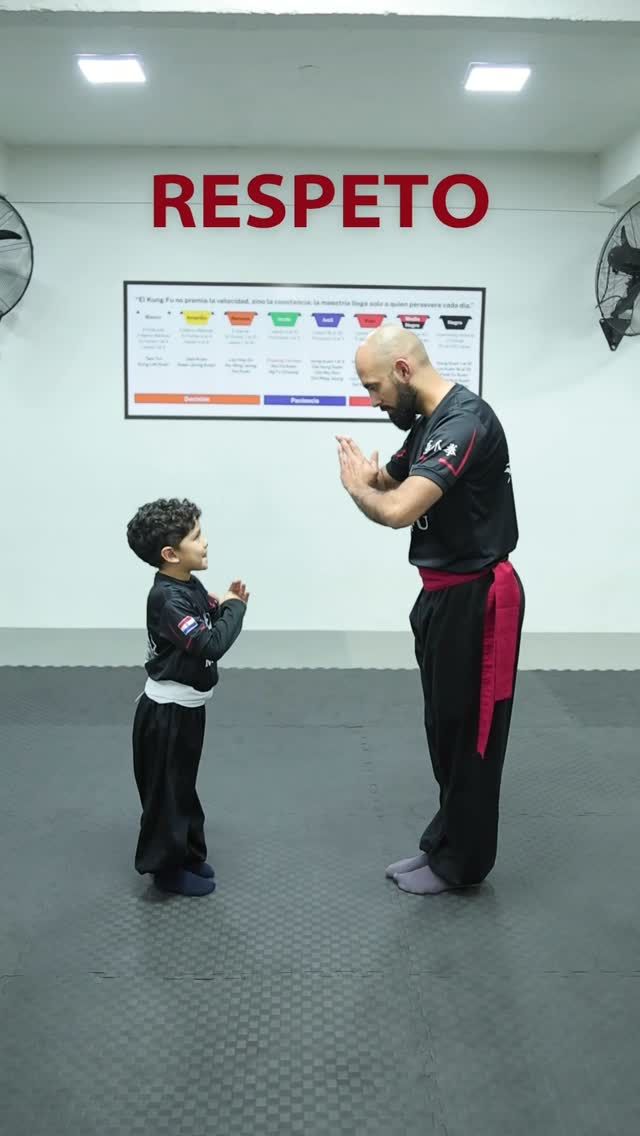 Un niño saluda a su maestro frente al cartel que dice Respeto